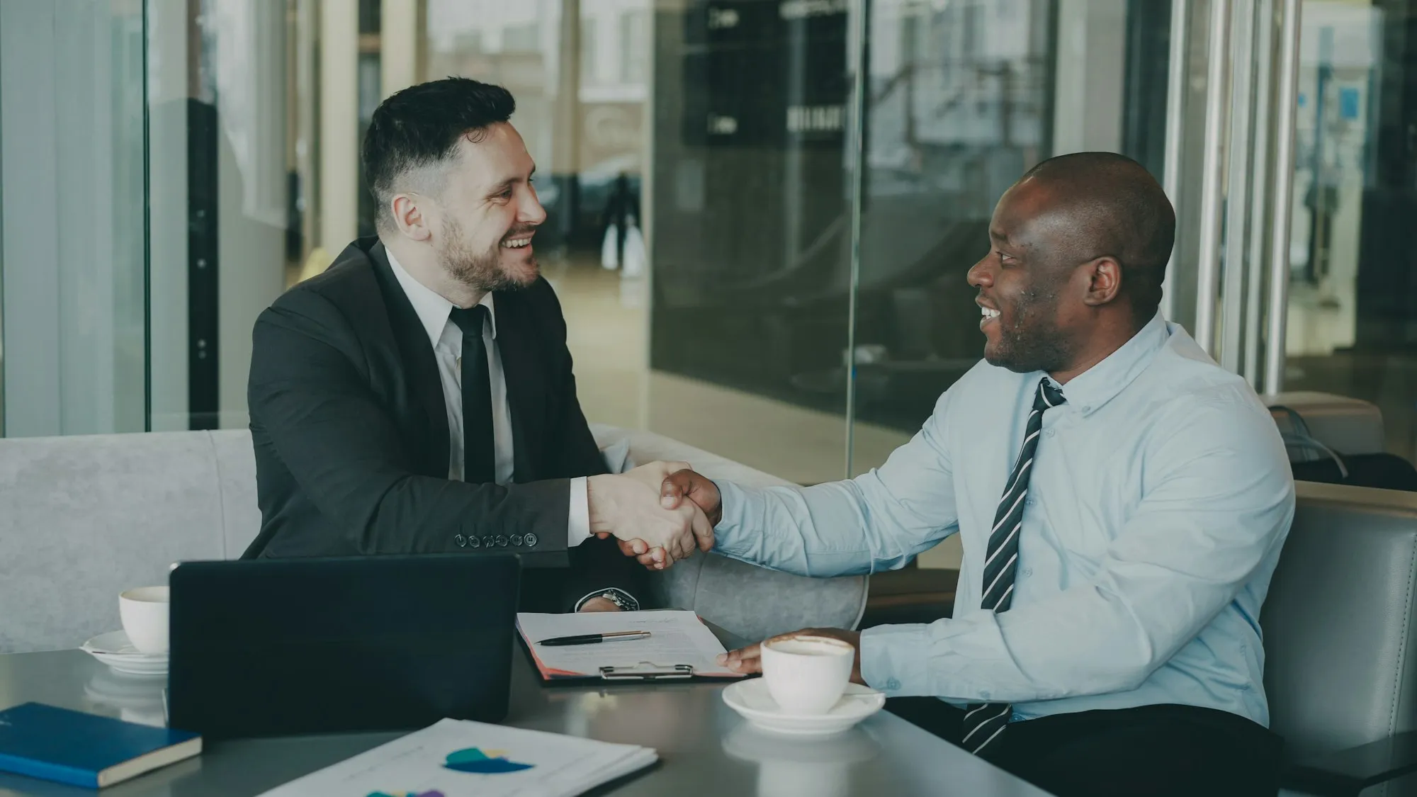 Two business partners shaking hands across a table